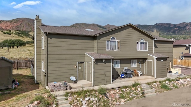 2480 Allegheny Dr, Colorado Springs, CO 80919 - rear view of house with a chimney, a mountain view, a patio, and an outbuilding