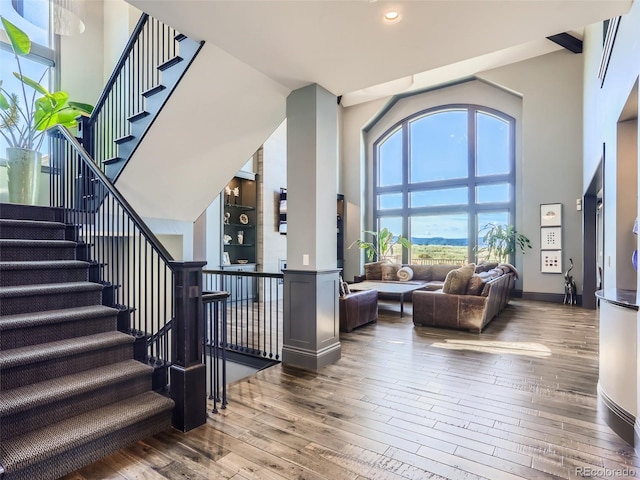 stairs featuring a towering ceiling and wood-type flooring