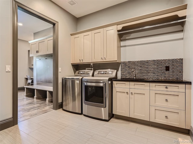 clothes washing area with cabinets, sink, and independent washer and dryer