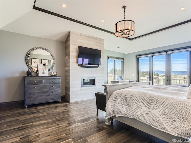 bedroom featuring dark wood-type flooring, access to exterior, a notable chandelier, ornamental molding, and a large fireplace