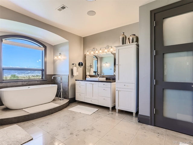 bathroom featuring tile patterned floors, vanity, a bath, and tile walls