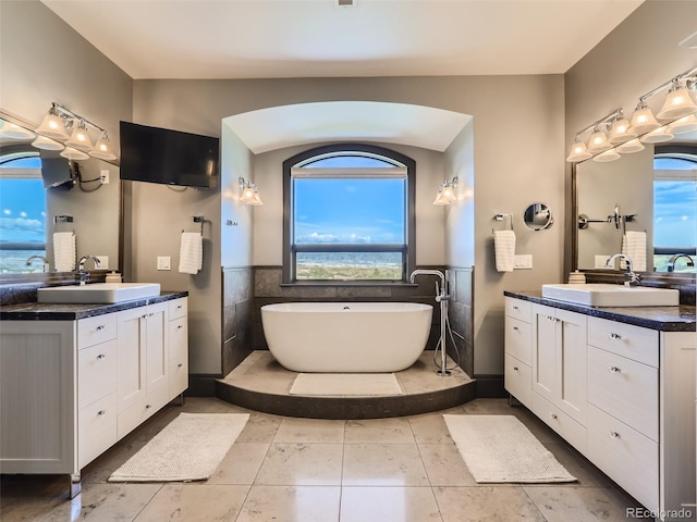 bathroom featuring tile patterned flooring, vanity, a tub, and tile walls