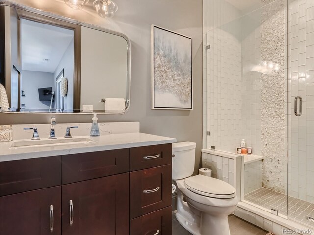 bathroom featuring vanity, a shower with door, and toilet