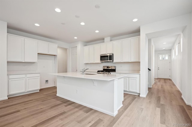 kitchen with white cabinets, sink, stainless steel appliances, and a kitchen island with sink