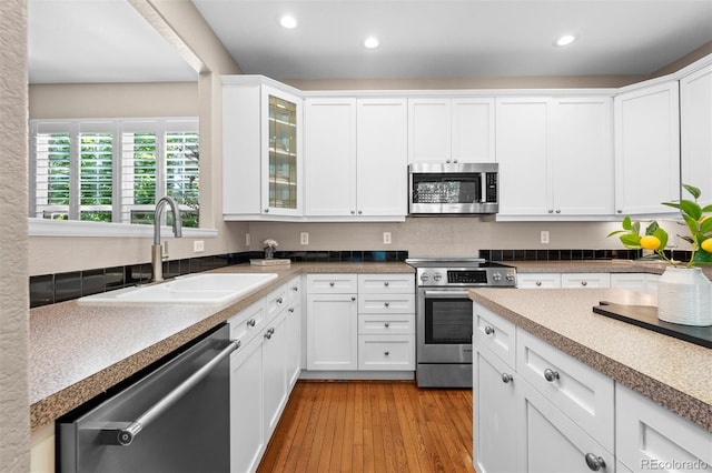 7746 E Severn Pl, Denver, CO 80230 - kitchen featuring stainless steel appliances, white cabinets, glass insert cabinets, recessed lighting, and wood finished floors