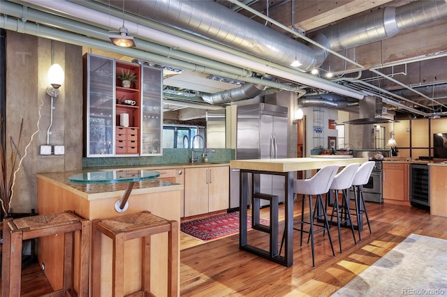 2000 Little Raven St Unit 1B, Denver, CO 80202 - kitchen featuring wine cooler, wood finished floors, island range hood, stainless steel appliances, and a sink