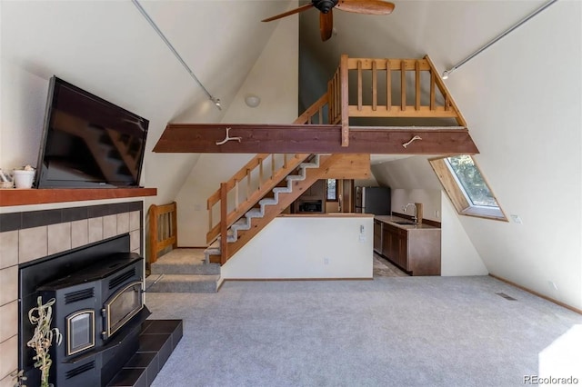 100 Aspen Ln, Evergreen, CO 80439 - unfurnished living room featuring a wood stove, stairs, ceiling fan, carpet flooring, and vaulted ceiling