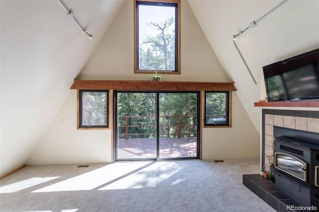 100 Aspen Ln, Evergreen, CO 80439 - unfurnished living room featuring rail lighting, a wood stove, lofted ceiling, carpet, and healthy amount of natural light