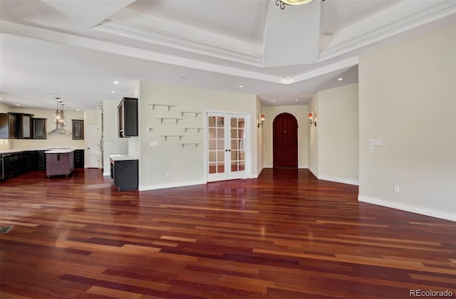 unfurnished living room with arched walkways, recessed lighting, baseboards, dark wood-style floors, and a raised ceiling