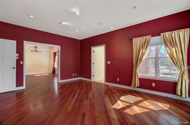 spare room with recessed lighting, an inviting chandelier, wood finished floors, and baseboards