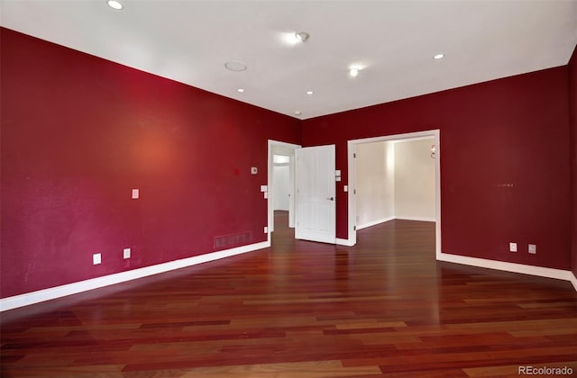 unfurnished room with visible vents, baseboards, and wood finished floors