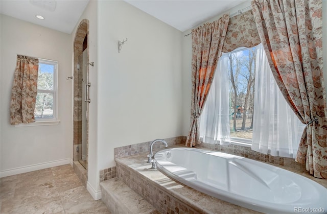 full bath with a stall shower, baseboards, and a garden tub