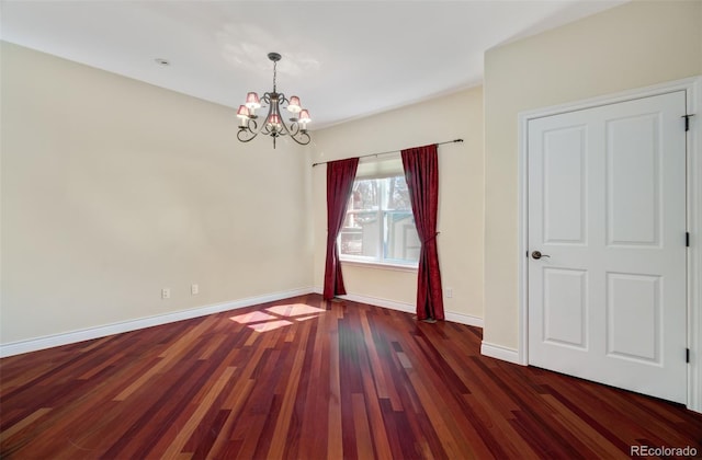 unfurnished room with a notable chandelier, baseboards, and wood finished floors