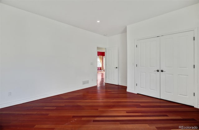 unfurnished bedroom featuring a closet, wood finished floors, visible vents, and baseboards