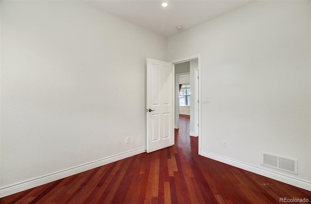 unfurnished room with baseboards, visible vents, and wood finished floors