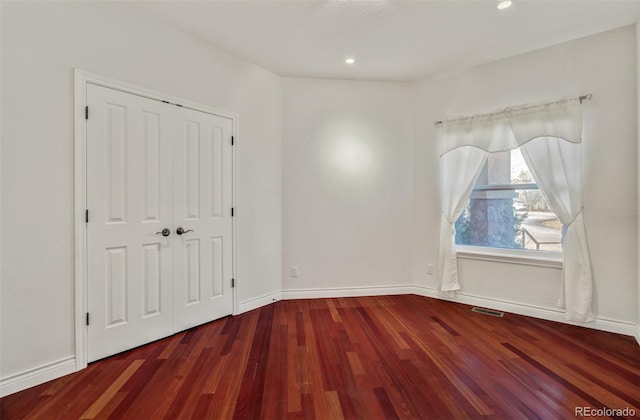 unfurnished bedroom with a closet, visible vents, baseboards, and wood finished floors