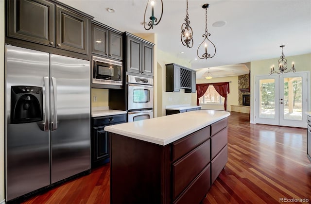 kitchen with french doors, dark wood finished floors, light countertops, a kitchen island, and built in appliances