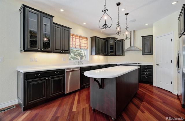 kitchen featuring visible vents, wall chimney range hood, stainless steel dishwasher, a center island, and dark wood finished floors