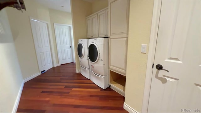 washroom featuring cabinet space, baseboards, dark wood-style floors, and washing machine and clothes dryer