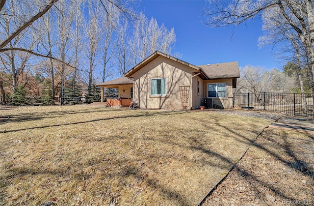 exterior space featuring a lawn, fence, and stucco siding