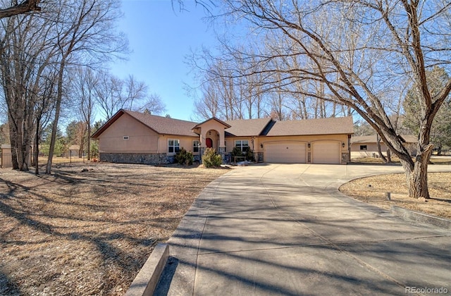 view of front of property featuring stucco siding, concrete driveway, an attached garage, fence, and stone siding