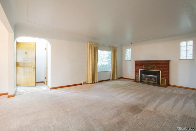 3222 Fenton St, Wheat Ridge, CO 80212 - unfurnished living room with light carpet, arched walkways, baseboards, and a brick fireplace