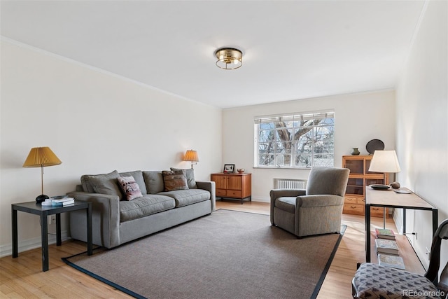 living room featuring ornamental molding, light wood finished floors, and radiator heating unit