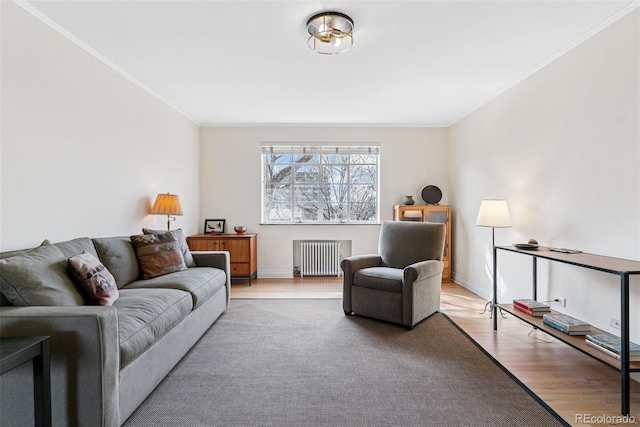 living area featuring radiator heating unit, crown molding, baseboards, and wood finished floors