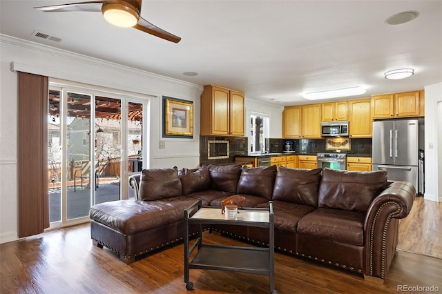 living area with ornamental molding, a ceiling fan, dark wood-style floors, and visible vents