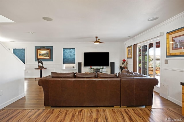 living room featuring baseboards, ornamental molding, ceiling fan, and wood finished floors