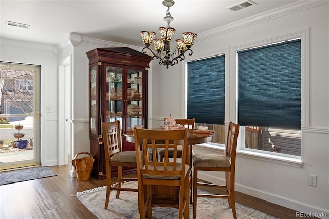 dining area with an inviting chandelier, crown molding, wood finished floors, and visible vents