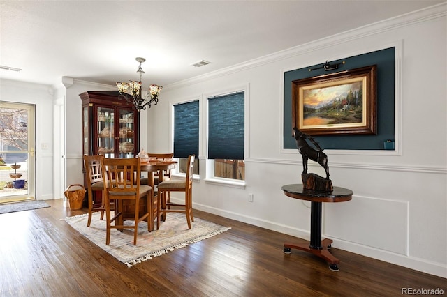 dining space with crown molding, an inviting chandelier, wood finished floors, and visible vents