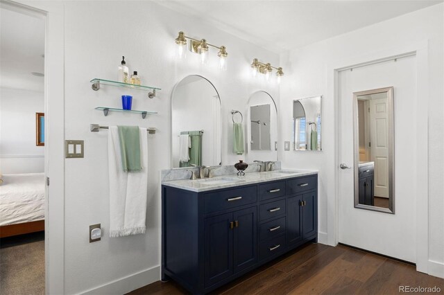 full bath with double vanity, a sink, connected bathroom, and wood finished floors