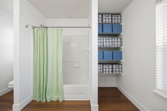 full bath featuring toilet, baseboards, wood finished floors, and shower / bath combo with shower curtain