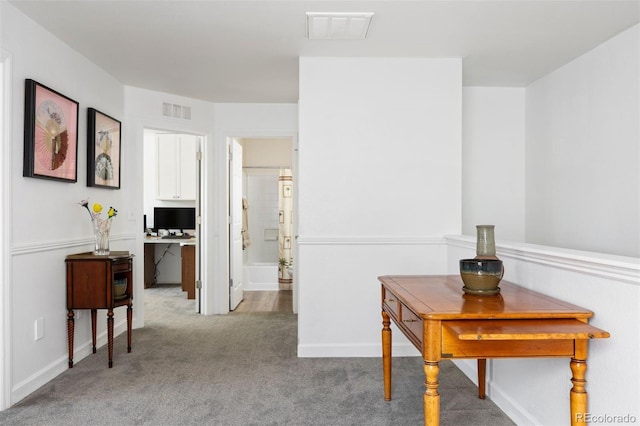 corridor with carpet floors, baseboards, and visible vents