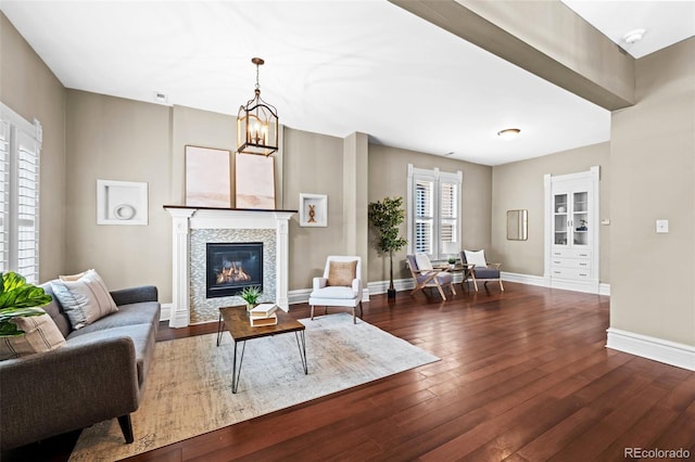 living area with hardwood / wood-style floors, a tile fireplace, baseboards, and a chandelier