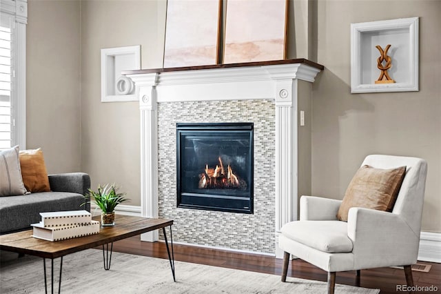 sitting room with wood finished floors, a tile fireplace, and baseboards