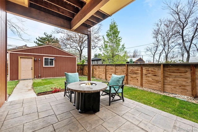 view of patio featuring a fenced backyard, an outbuilding, and an outdoor fire pit
