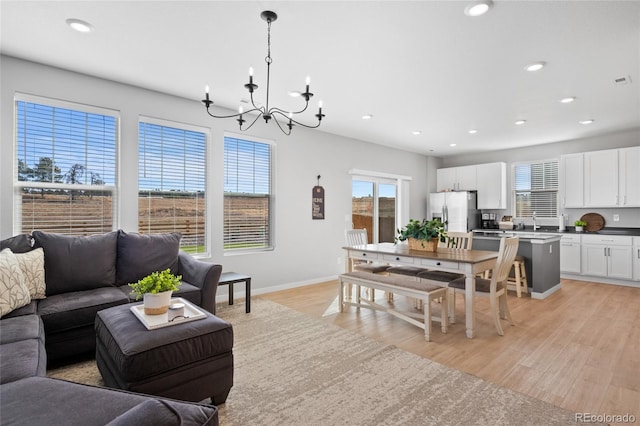 living area featuring a chandelier, recessed lighting, light wood finished floors, and baseboards