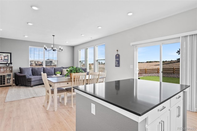 kitchen with light wood-type flooring, a notable chandelier, dark countertops, recessed lighting, and white cabinets