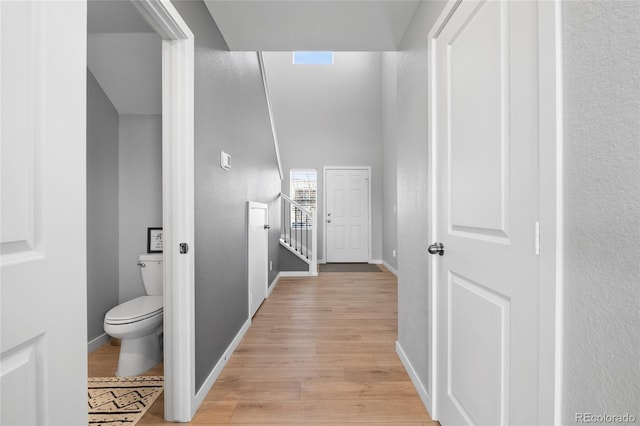 corridor with baseboards and light wood-style floors