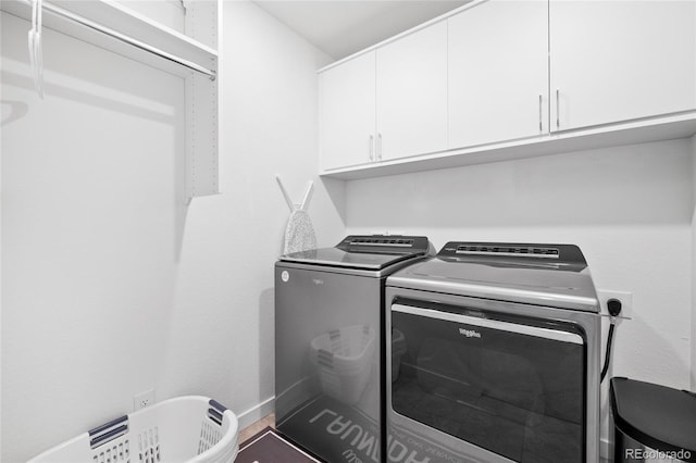 washroom with cabinet space, baseboards, and washer and clothes dryer