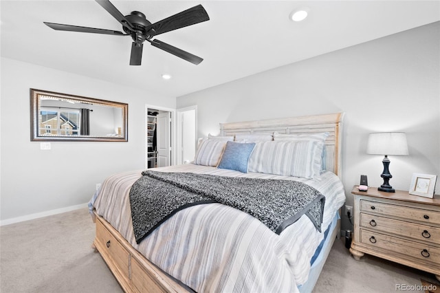 bedroom with a ceiling fan, baseboards, recessed lighting, light carpet, and a walk in closet