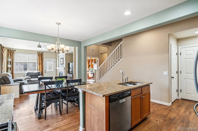 kitchen with brown cabinets, stainless steel dishwasher, open floor plan, a sink, and wood finished floors