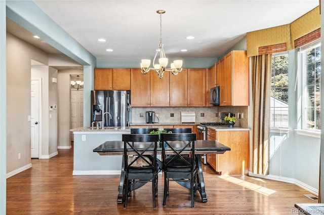 kitchen featuring a chandelier, stainless steel appliances, backsplash, and wood finished floors