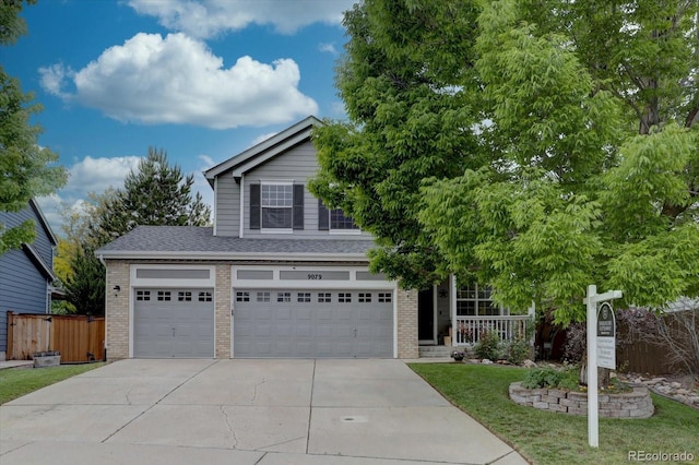 9079 Garnet St, Highlands Ranch, CO 80126 - view of property hidden behind natural elements featuring brick siding, concrete driveway, an attached garage, a porch, and a shingled roof