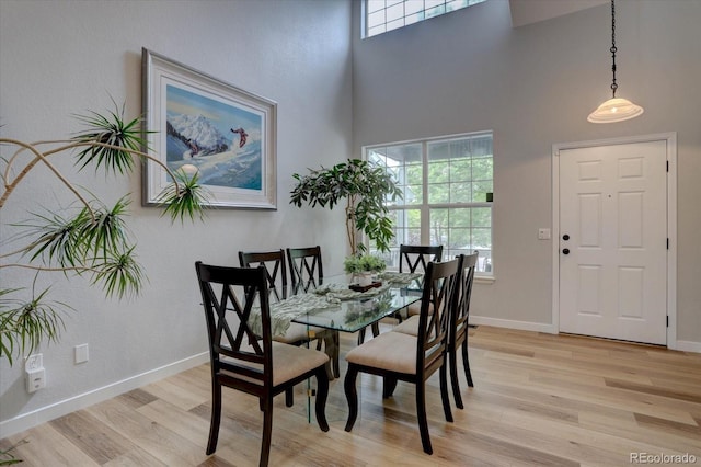 9079 Garnet St, Highlands Ranch, CO 80126 - dining area with light wood-style flooring, plenty of natural light, a high ceiling, and baseboards