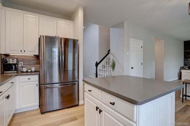 9079 Garnet St, Highlands Ranch, CO 80126 - kitchen with freestanding refrigerator, dark countertops, light wood-type flooring, backsplash, and white cabinetry