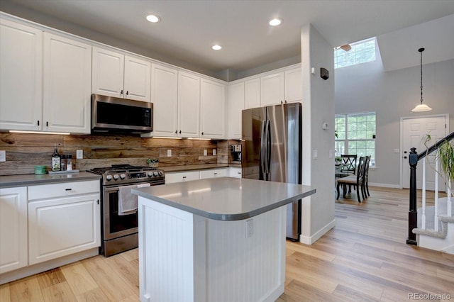 9079 Garnet St, Highlands Ranch, CO 80126 - kitchen with stainless steel appliances, white cabinets, light wood finished floors, backsplash, and recessed lighting