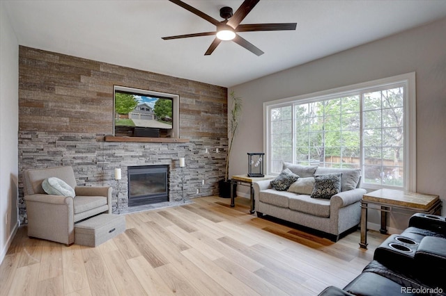 9079 Garnet St, Highlands Ranch, CO 80126 - living area with a ceiling fan, a stone fireplace, light wood finished floors, wooden walls, and an accent wall